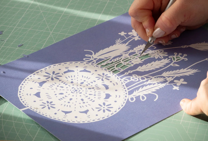un main découpe du papier en gros plan, technique du Papercut
